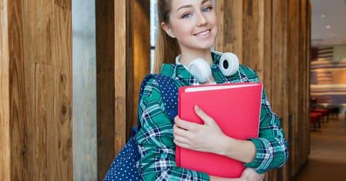 Woman Standing in Hallway While Holding Book