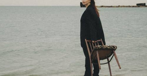 Woman on a Beach Standing and Holding a Chair 