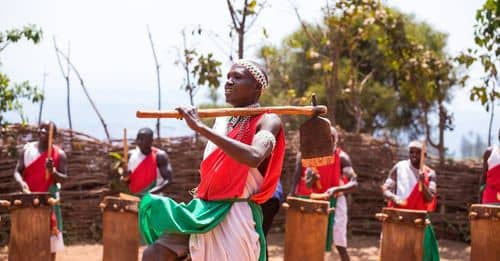 A man in a red and green outfit is playing drums