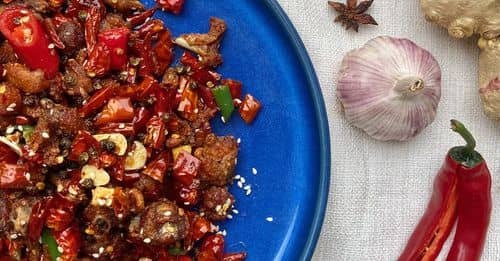 A blue plate with meat and spices on it