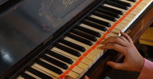 A person playing a piano with a red and white striped ribbon