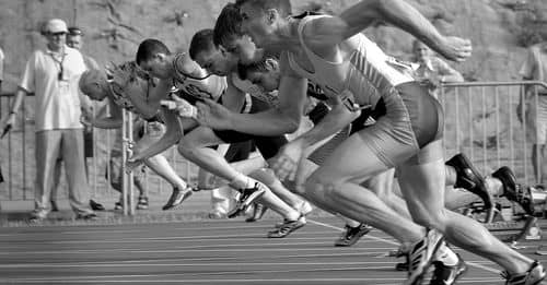 Athletes Running on Track and Field Oval in Grayscale Photography