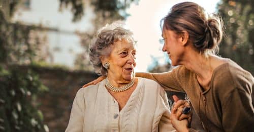 Joyful adult daughter greeting happy surprised senior mother in garden