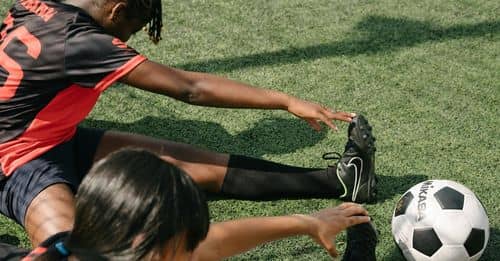 From above of young African American female soccer players warming up during practice