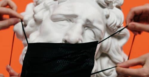 People Holding Mask Over A Sculpture