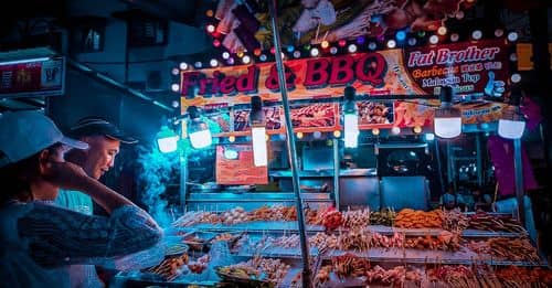 Customer choosing raw kebab in street stall at night