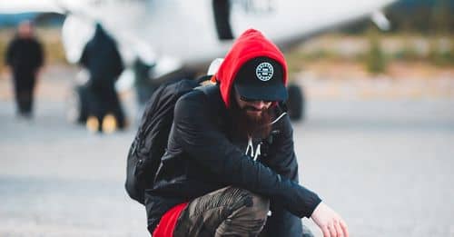 Bearded male traveler hunkering down near light aircraft