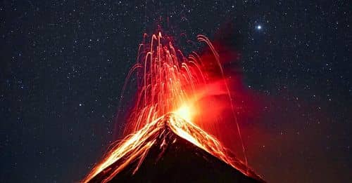 Volcano Erupting at Night Under Starry Sky