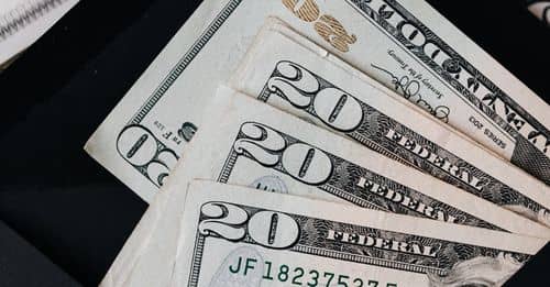 Stack of dollars and black envelope with banknotes inside