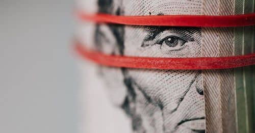 Closeup of rolled United States five dollar bills tightened with red rubber band