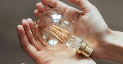 Unrecognizable woman demonstrating light bulb in hands