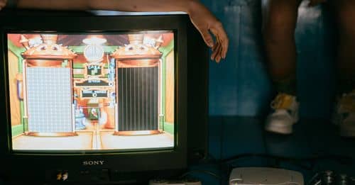 Crop unrecognizable female on modern monitor with video game on screen near ethnic partner