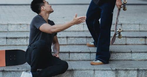 Content Asian male friends clapping each other hands on street