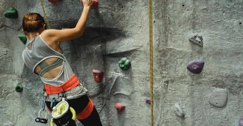 Unrecognizable climber ascending artificial rock with holds