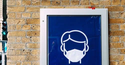 Signboard with reminder to wear face mask on building wall