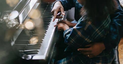 Side view high angle of African American father and daughter playing acoustic piano during Christmas celebration