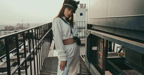 Stylish woman in hat standing on rooftop