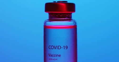 A Close-Up View of a Covid-19 Vaccine Vial on Blue Background