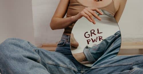 Woman in Brown Tank Top and Blue Denim Jeans Holding Round Mirror