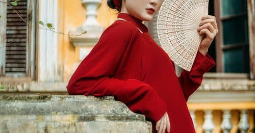 Gorgeous Asian woman with hand fan outside weathered old building