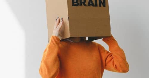 Crop person putting Idea title in cardboard box with Brain inscription on head of female on light background