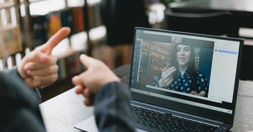 Young lady learning sign language during online lesson with female tutor