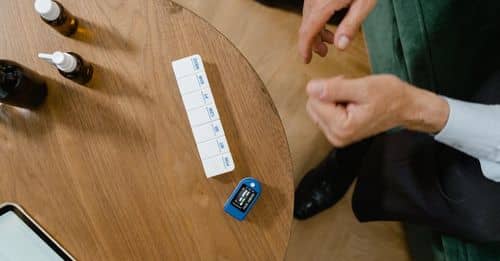 Elderly Man Sitting on a Couch and Medicine and Pills on a Table 