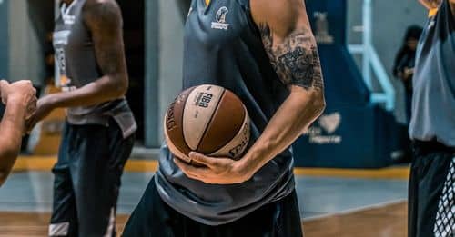 Man in Gray Sleeveless Shirt Carrying White and Brown Spalding Basketball