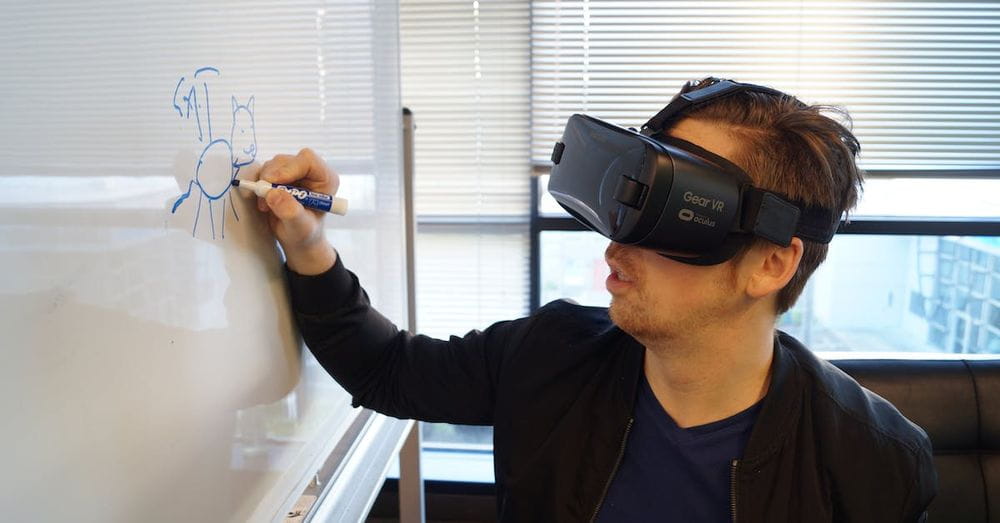 Person Wearing Black Vr Box Writing On White Board