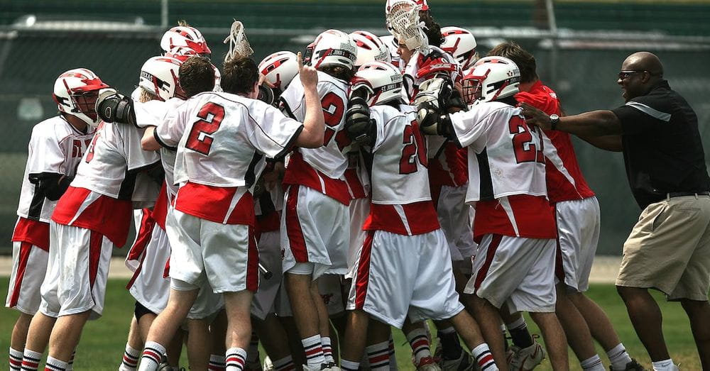 Group of Lacrosse Players Celebrating With Coach during Daytime