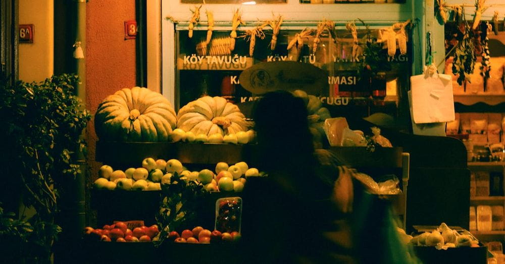 Person Walking near Market with Fruit and Vegetables at Night