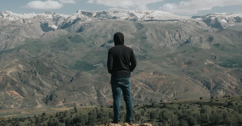 A person standing on top of a rock looking at the mountains