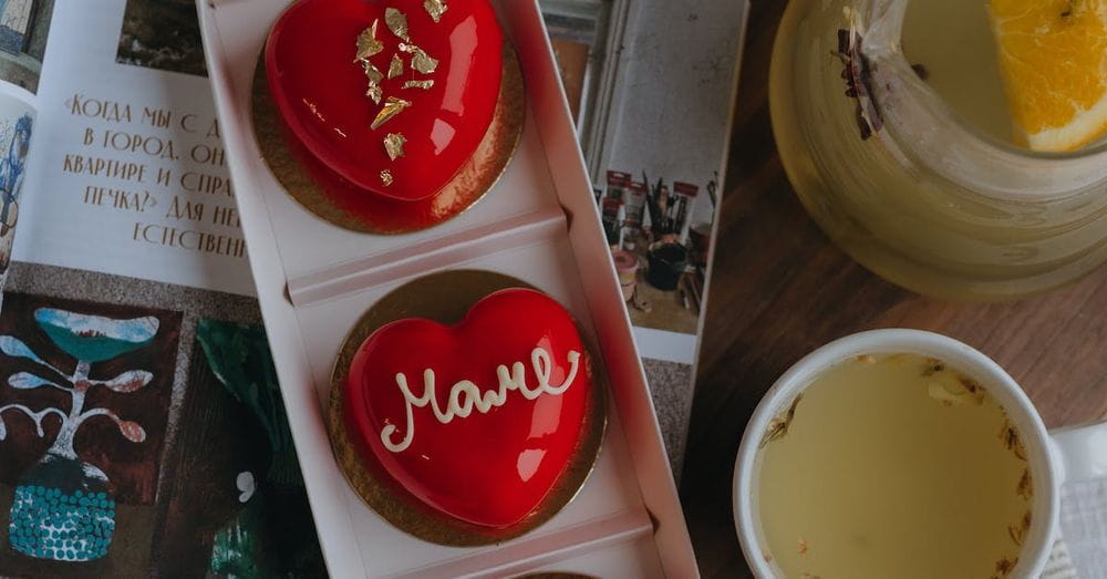 A tray with three heart shaped cookies and a cup of tea