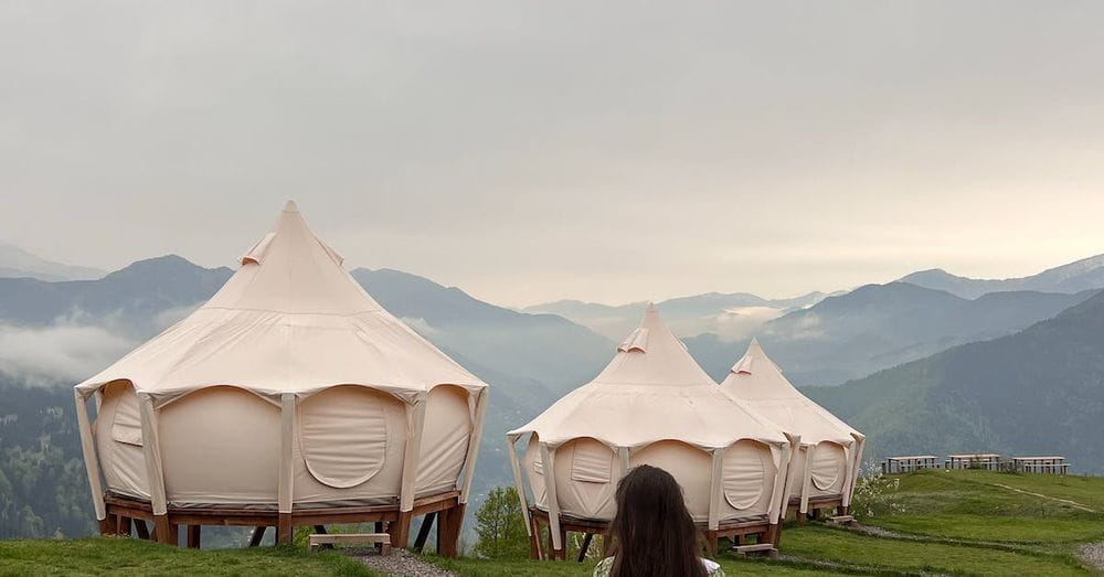 A woman walking through a field with a bunch of tents