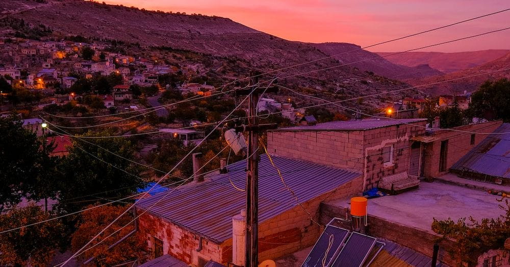 A sunset over a town with houses and power lines