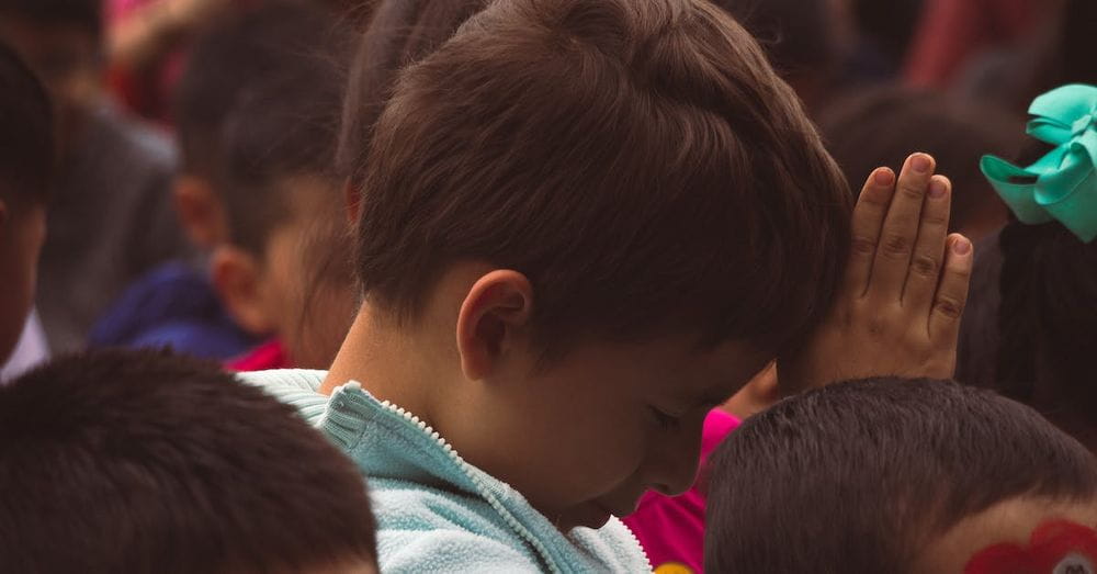 A child is praying in front of a crowd