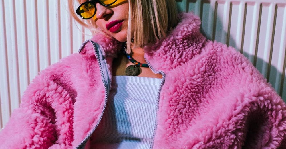 A woman in sunglasses and a pink fuzzy jacket