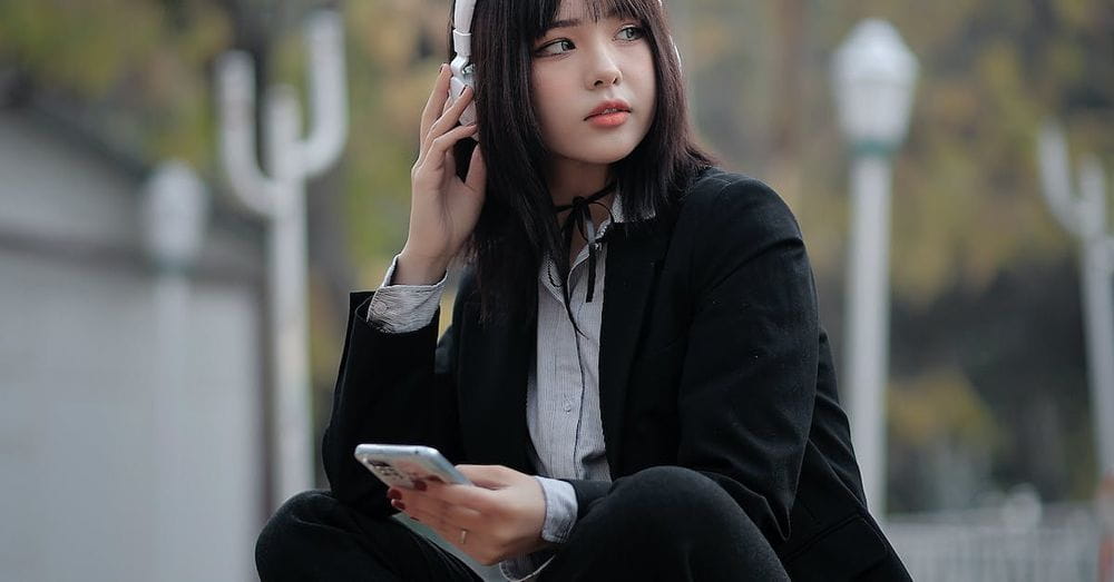 A woman sitting on the ground with headphones on