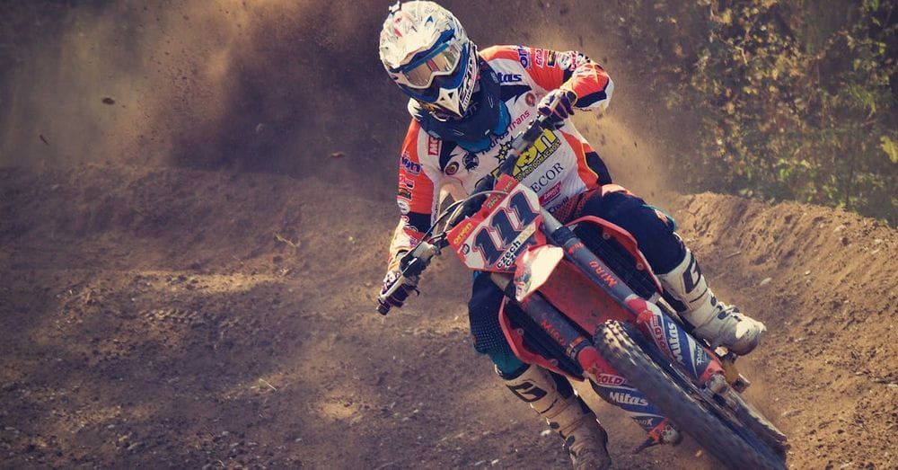 Man in White and Orange Motocross Overall Riding His Motocross Dirt Bike during Daytime