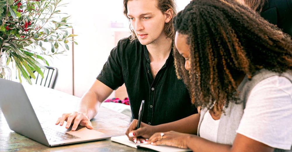 Man Working on Laptop while Woman Takes Notes