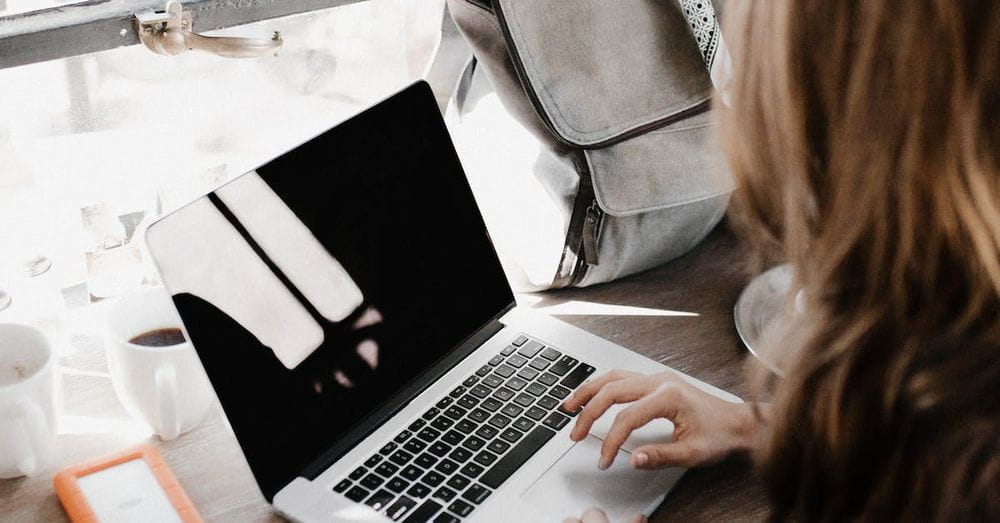 Close-up Photography of Woman Sitting Beside Table While Using Macbook