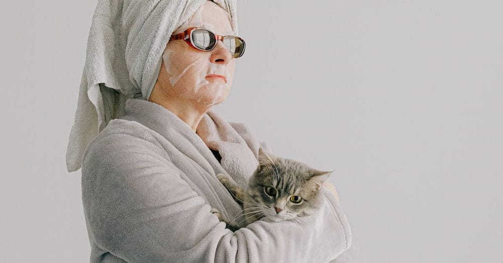 Woman after bath standing with cat in arms