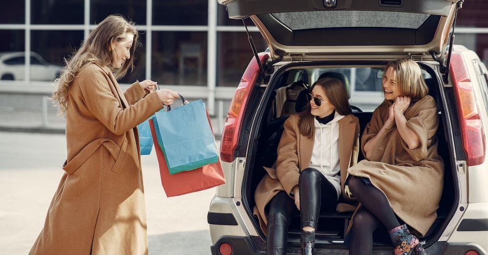 Young woman demonstrating shopping bags to friends