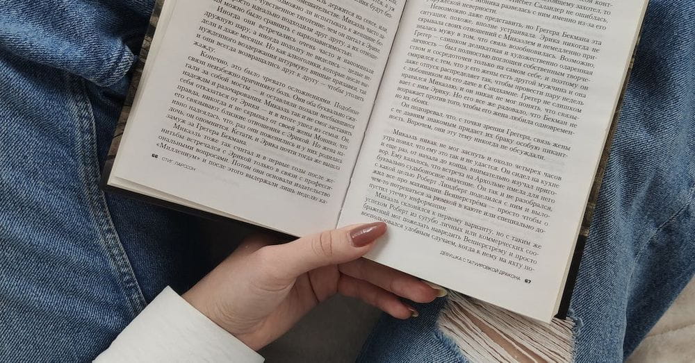 Crop faceless woman reading book on bed