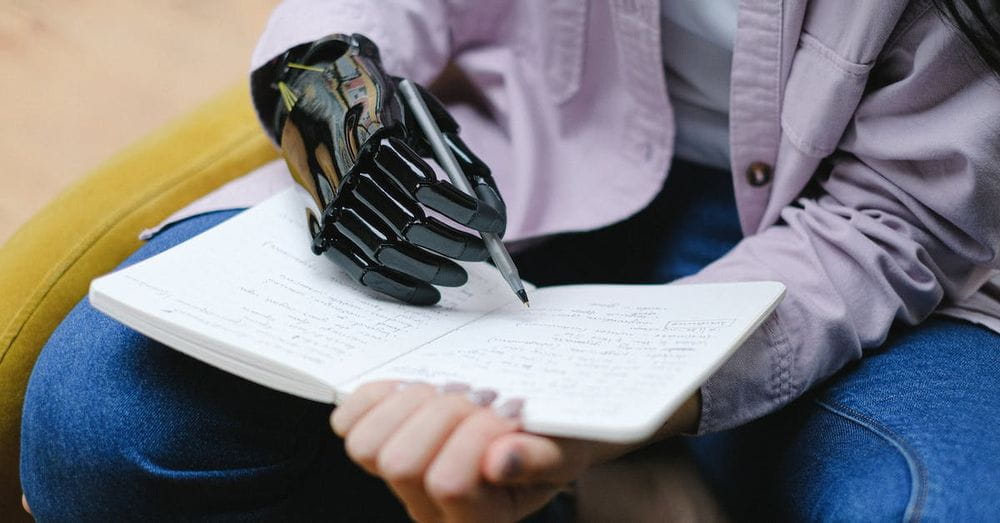 Woman with modern prosthesis of hand writing in notebook