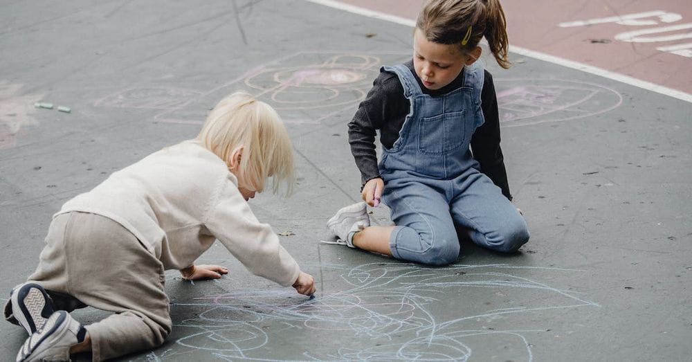 Adorable girls drawing on asphalt