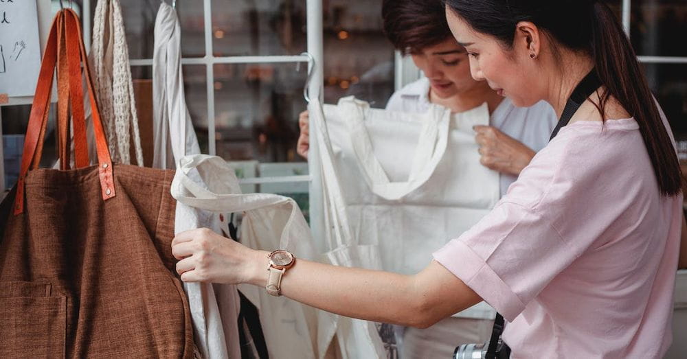 Trendy young Asian women choosing cotton bags in fashion boutique