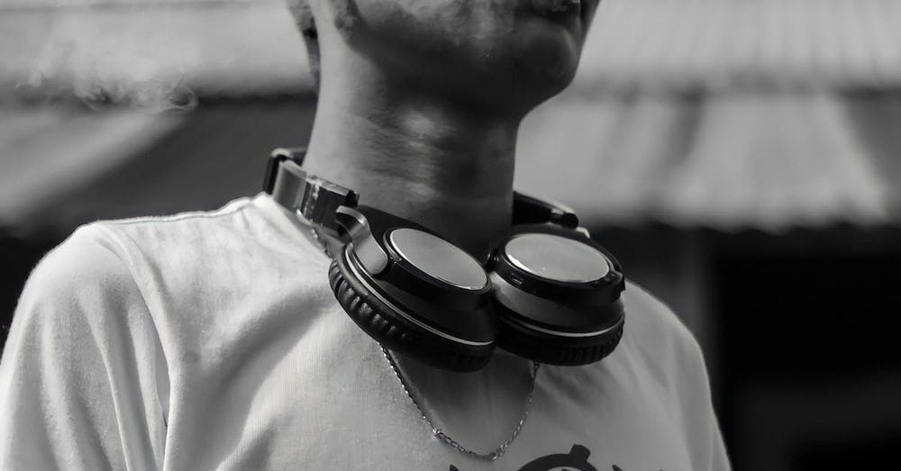 Young male hipster with headphones around neck smoking outdoors