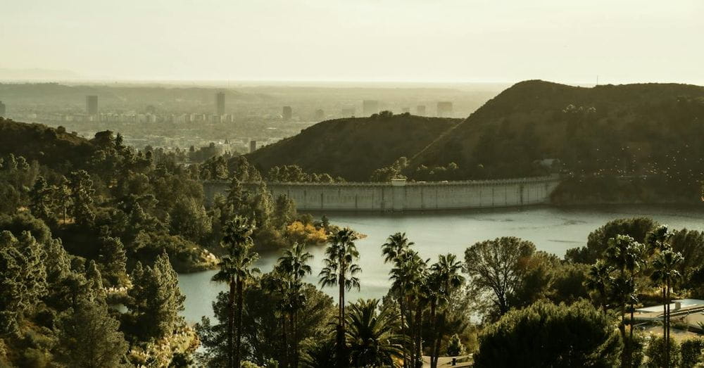 Amazing scenery of Hollywood Reservoir and dam amidst green verdant trees and hills in California on sunny day