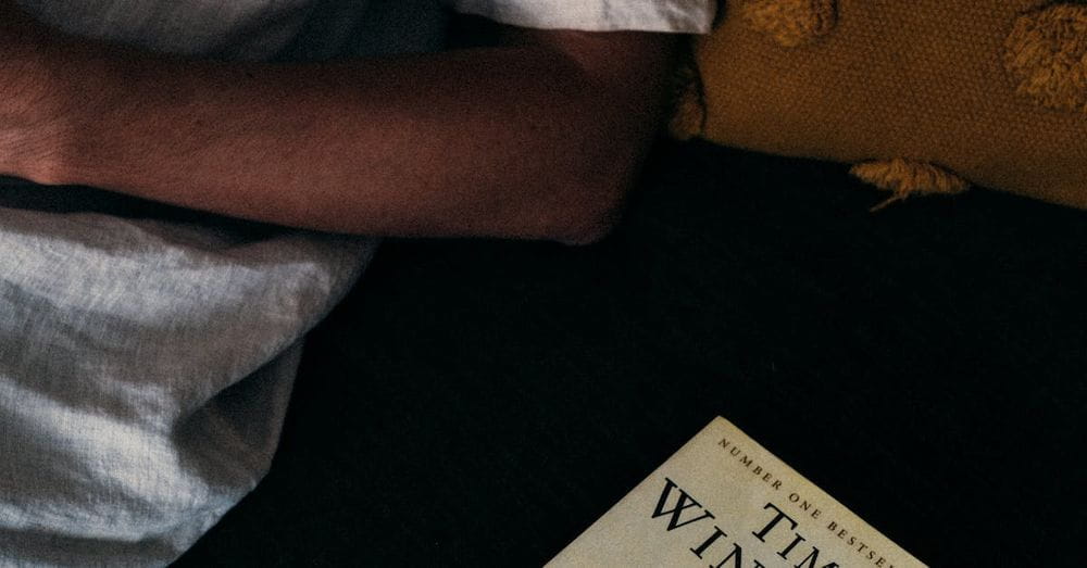 Close-Up Shot of a Person beside a Novel Book